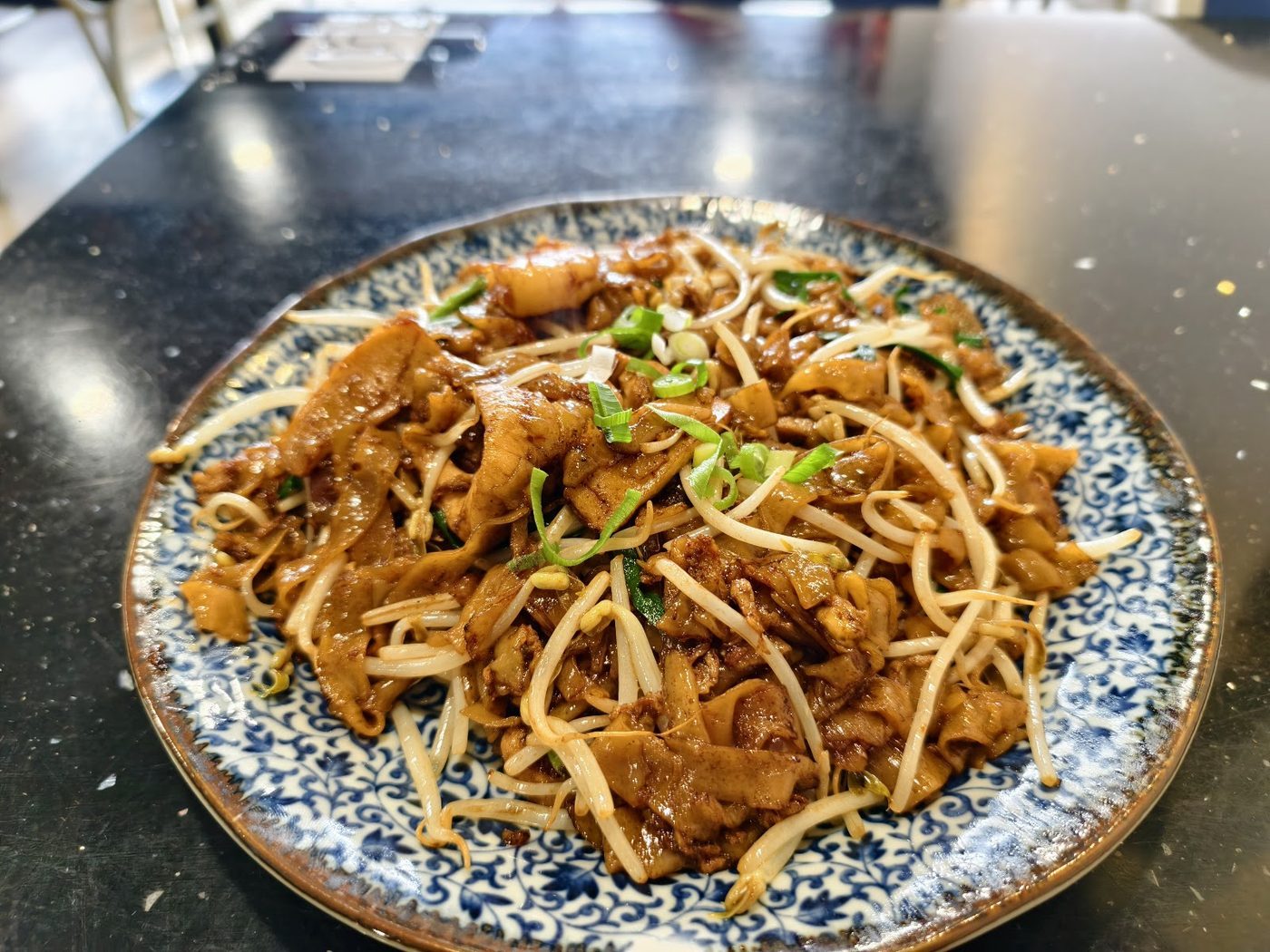 A plate of wok-tossed noodles with sliced vegetables and savoury toppings